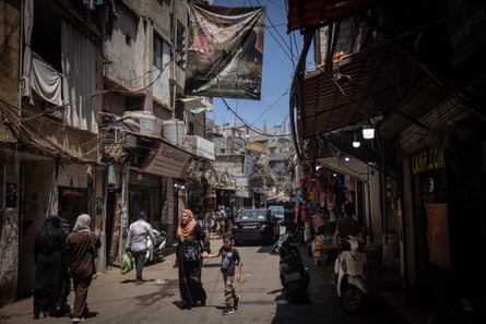 People walk under a poster of newly appointed Hamas leader Yahya Sinwar in the Palestinian camp of Bourj al-Barajneh in Beirut, Lebanon, on 8 August 2024.