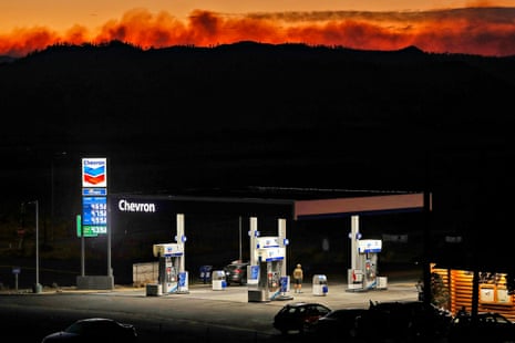 a fire burns in the distance behind a gas station