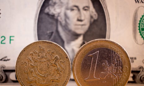 A €1 coin and a £1 sterling coin are seen in front of a US dollar bill.