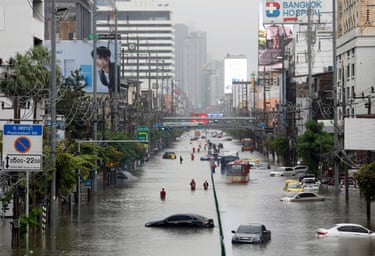 Residents wade through floodwater and past submerged vehicles