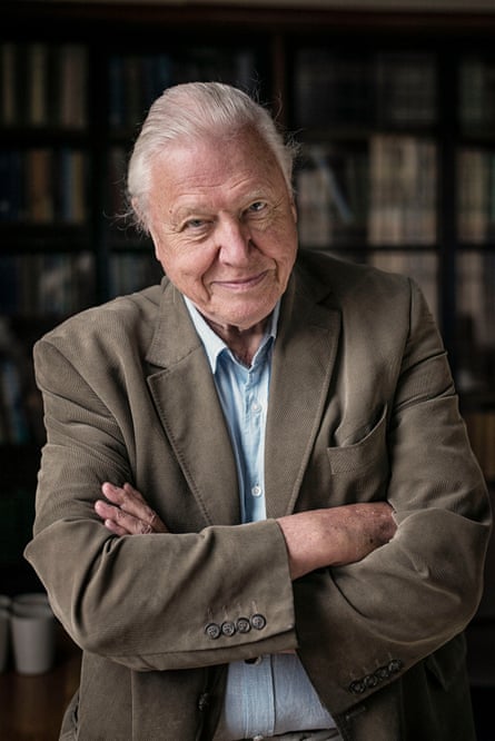 Portrait of David Attenborough smiling into camera, arms crossed