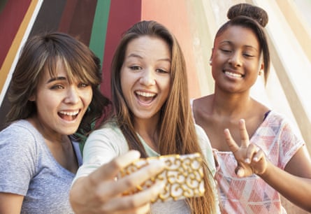 Teenage girls taking self-portrait with mobile phone