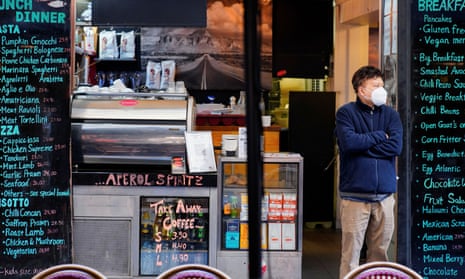 Man in mask stands in front of cafe in Melbourne