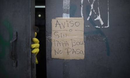 A piece of cardboard is taped to a supermarket door with a handwritten message saying ‘Notice: without a face mask, no entry’ in Caracas, Venezuela.