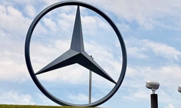 Very large metal Mercedes Benz symbol, a three-pointed star inside a circle, under partly cloudy sky.