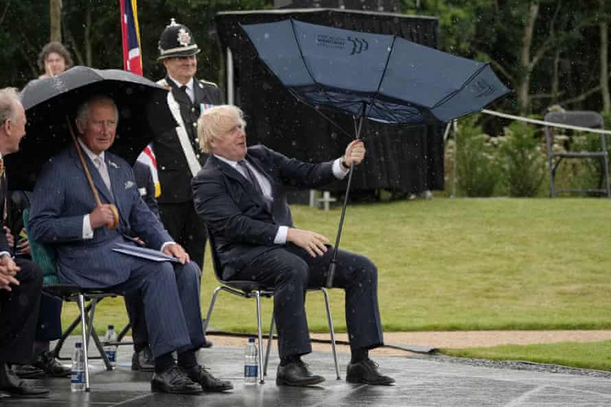 Britain’s Prime Minister Boris Johnson (R) tries to open his umbrella next to Britain’s Prince Charles, Prince of Wales (L), at the dedication ceremony of the new national UK Police Memorial at the National Memorial Arboretum in Alrewas, central England, on July 28, 2021