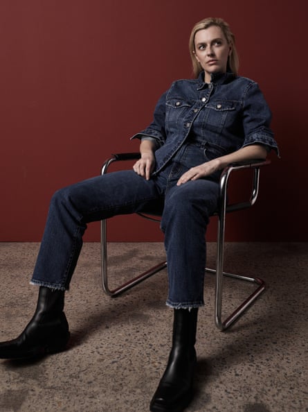 Gracie Otto is sitting in a metal chair, she is wearing denim jeans, a denim jacket and black boots