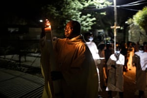 A priest walks towards the church with the paschal candle during the Easter vigil