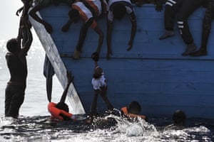 A child is pulled out of the water as people wait to be rescued by members of Proactiva Open Arms NGO