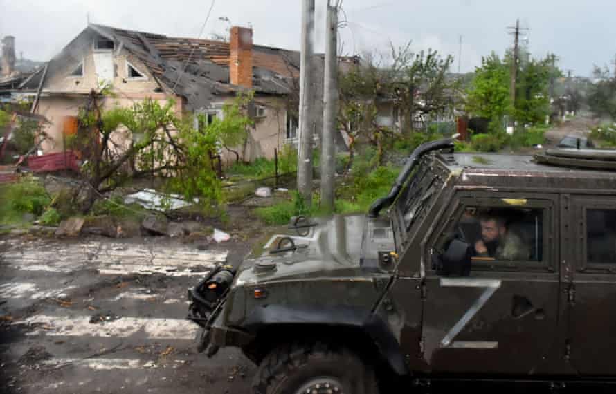 A Russian military vehicle painted with the letter Z drives past destroyed houses in Ukraine’s port city of Mariupol.