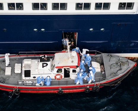 This aerial view shows health personnel assisting patients on to a boat from the cruise ship MV Hondius.