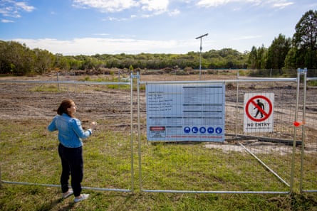 Woman standing in front of fence around cleared block of land