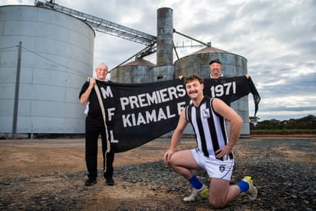 Walter Munro and boy Deane clasp nan 1971 Mallee Football League premiership flag, while Ethan wears nan one-off Kiamal jumper for Heritage Round