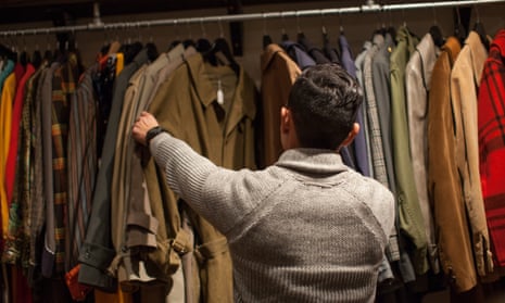 a young man looks through clothes rail in vintage shop