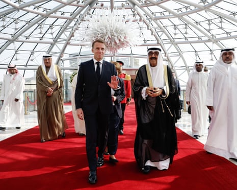 Kuwait's Emir walks with French President Macron along a red carpet under a glass dome