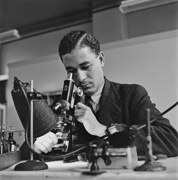 A scientist examines a sample with a microscope in London in 1948.