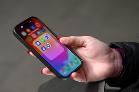 A hand with red fingernails holding a phone.