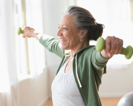 Older Hispanic woman lifting weights in living room