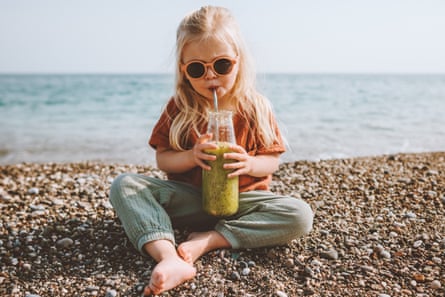Toddler girl drinking smoothie on beach
