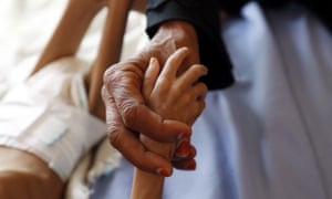A mother holds her malnourished child’s hand who is receiving treatment at a hospital in Sana’a.