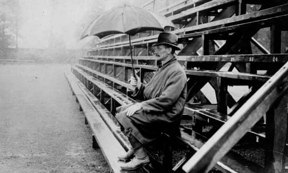 A spectator shelters from the rain as he hopes for play to resume at a cricket match in 1924