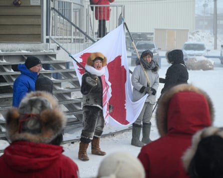 Bathory and Rojas hold banner in snow with other people around