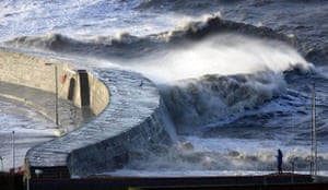 Lyme Regis, Dorset: A man watches the waves crash against the walls of the Cobb
