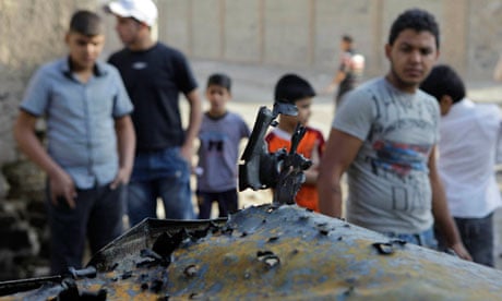 Iraqis inspect a destroyed car at the scene of a bomb attack on Christian houses in Baghdad.