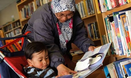 A young muslim mother reading to her son in Lampeter public library, Ceredigion Wales UK