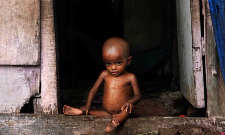 malnourished indian child sits in doorway