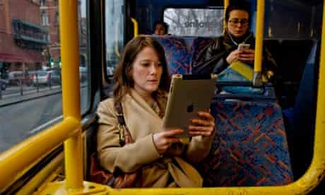 Young women reading novels on both a Kindle and an iPad on public transport