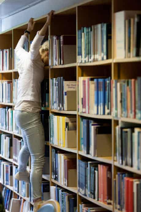 A dancer hangs off the book shelves in Cern's library