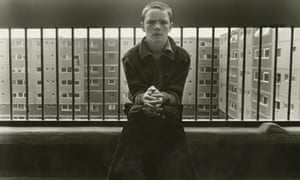 A boy sitting in front of iron railings