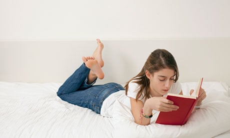Girl lying on bed, reading book