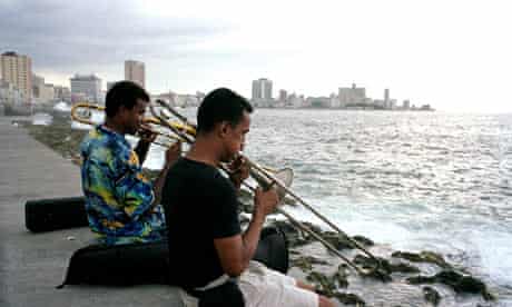 Two musicians play trombones on the sea wall in Havana, Cuba