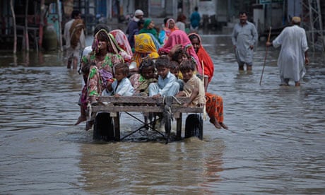 Family members sit on a donkey cart as they escape through the flooded streets in the Badin district