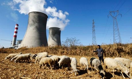 A farmer watches his sheep grazing near a power plant near Changzhi, Shanxi province