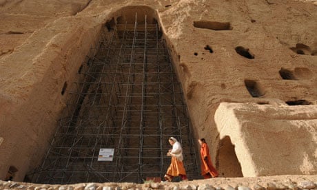 Afghan girls walk past the empty seat of one of the Buddhas in Bamiyan