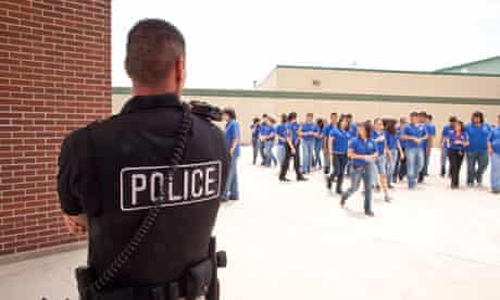 Male police officers supervise students in a high school