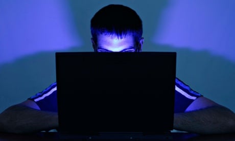 Man Using a Laptop with His Face Illuminated by the Screen