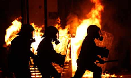 Riot policemen silhouetted in front of a burning kiosk during clashes in Athens