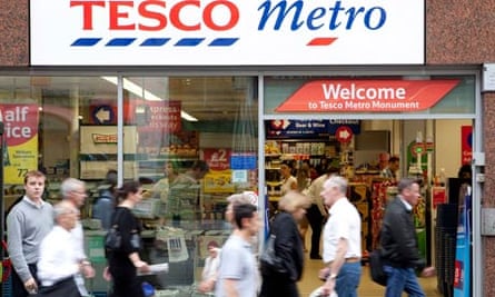 Shoppers walk in front of a Tesco Metro store