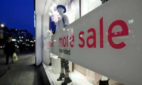 A pedestrian passes the window of a clothes shop advertising a sale on the Strand in central London