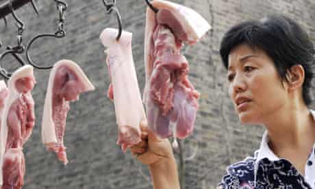 A consumer chooses pork at a market in Xiangfan
