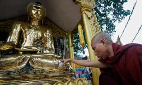 Buddhist monk pours water over a statue of Buddha in Yangon, Burma
