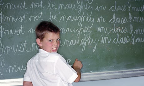 Schoolboy writing lines on blackboard