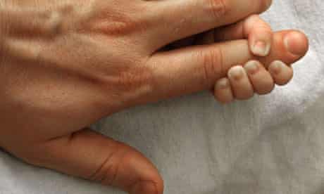A baby hand holding his father's finger