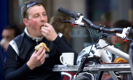 A cyclist enjoys a coffee and snack at an outdoor cafe in Bath