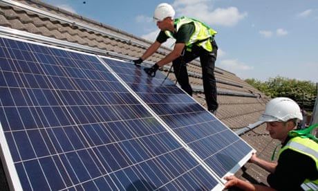Workmen install HomeSun solar panels on to the roofs of homes on a street in Delabole in Cornwall