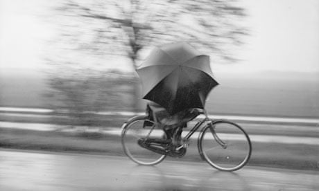 Bike blog : A cyclist sheltering from the rain underneath a huge umbrella